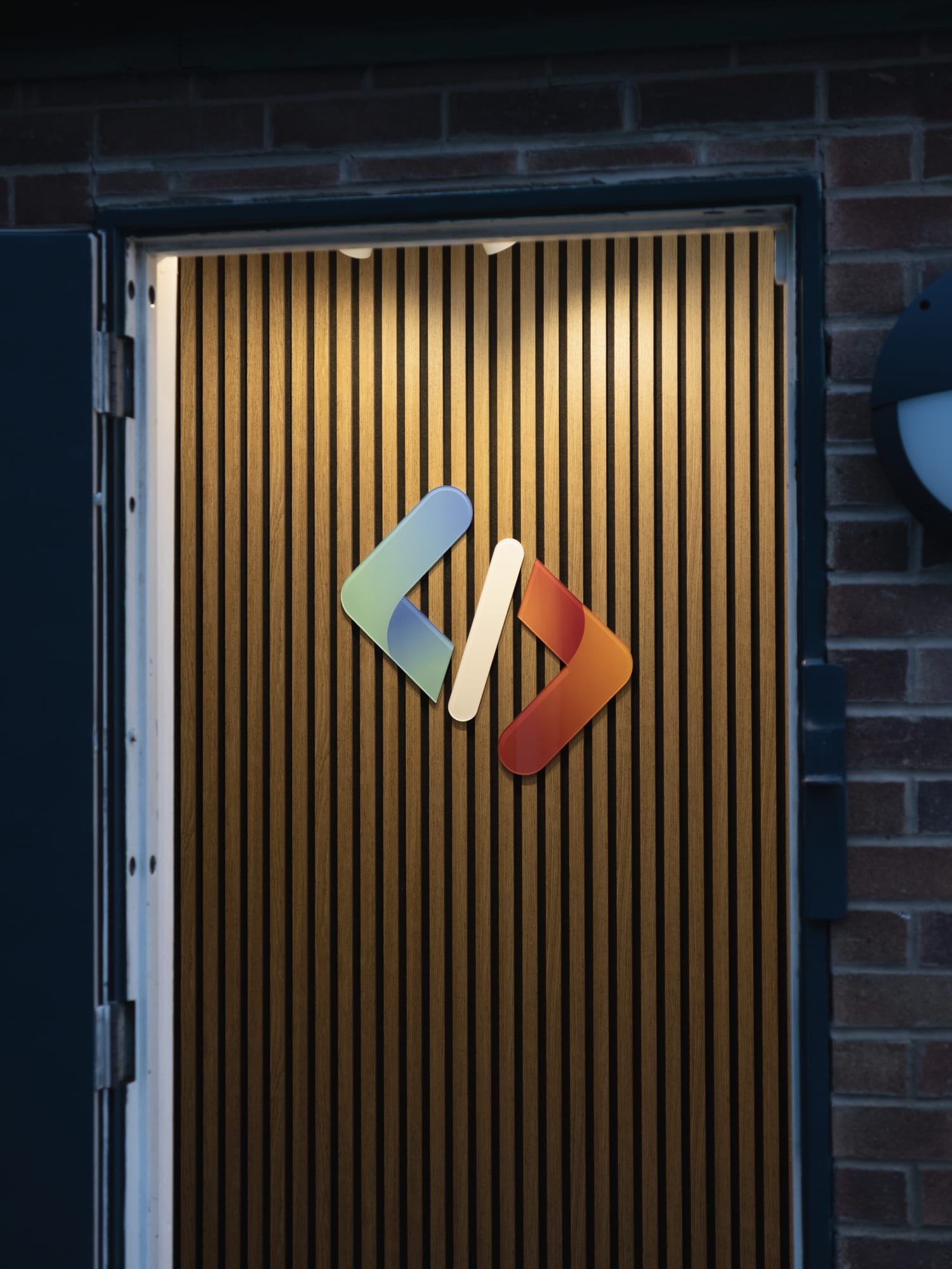 The Garman Technology door, with the logo lit on a slatted wall